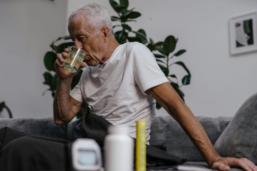 Disabled elderly man taking medications, using Life Backup Plan's medication reminder feature and Life Log to log what medications he took and when, to better inform his physician