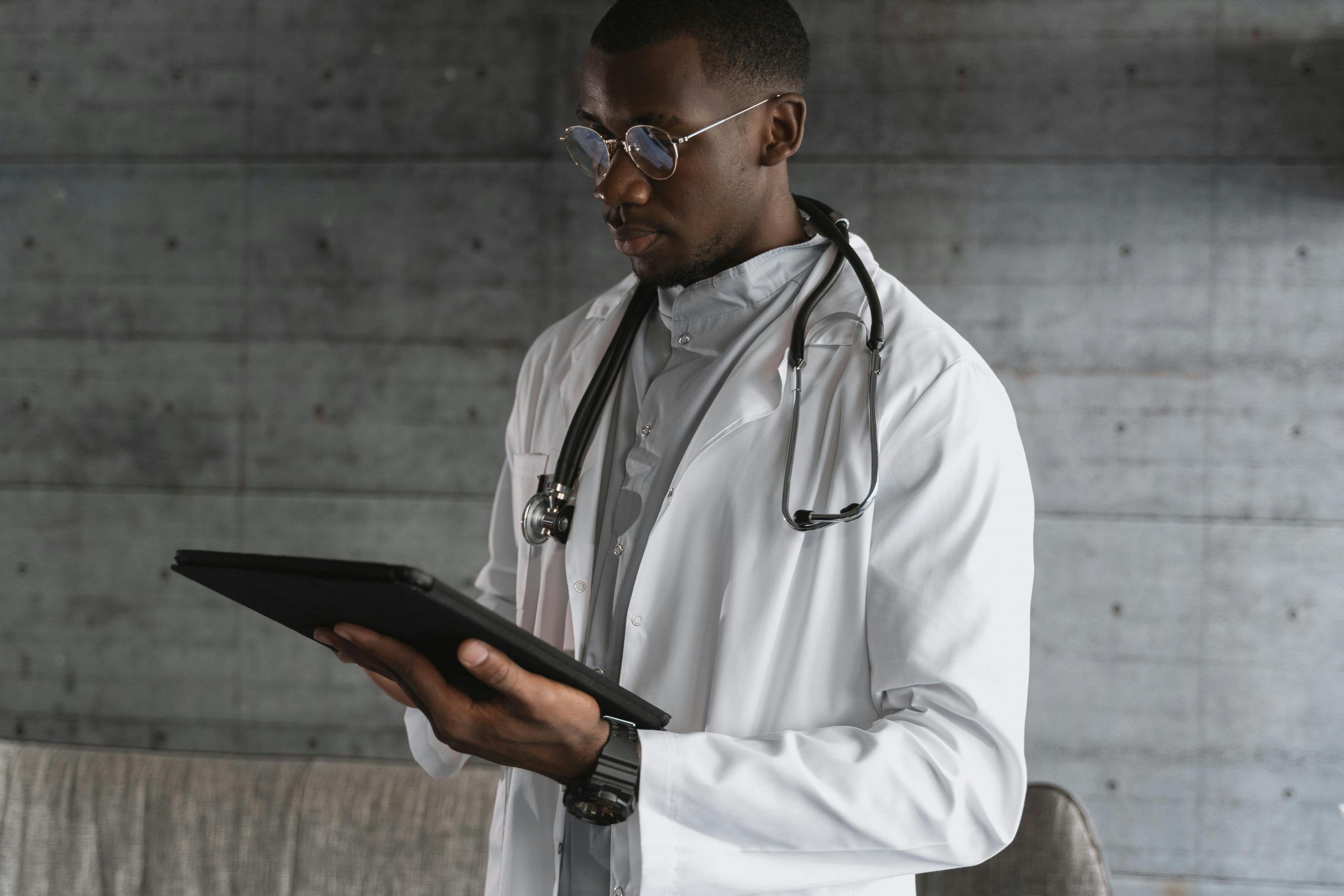 African American Male Physician using Life Backup Plan Digital Health and Safety mobile app to improve patient experience and health outcomes on a tablet. He relies on the medical, social, surgical and medication history of Life Backup Plan to better inform his treatment decisions.