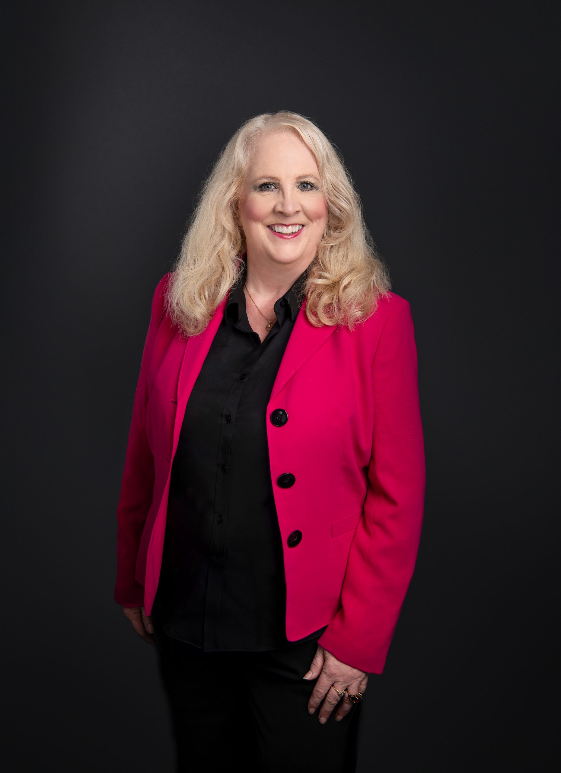 Sandy black blouse and pants, fuchsia jacket standing Life Backup Plan Founder and CEO Sandy Eulitt standing in a very welcoming pose in a black blouse, black pants and a fuchsia jacket
